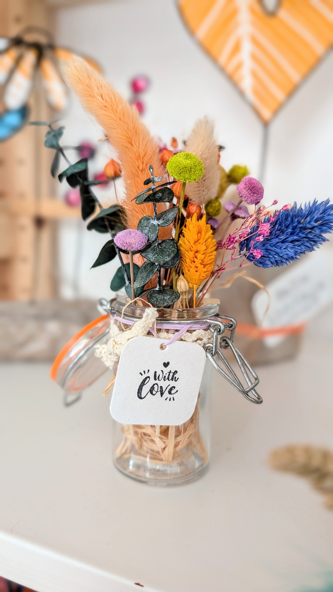 Glas mit buntem Trockenblumenstrauß und Anhänger „With Love“