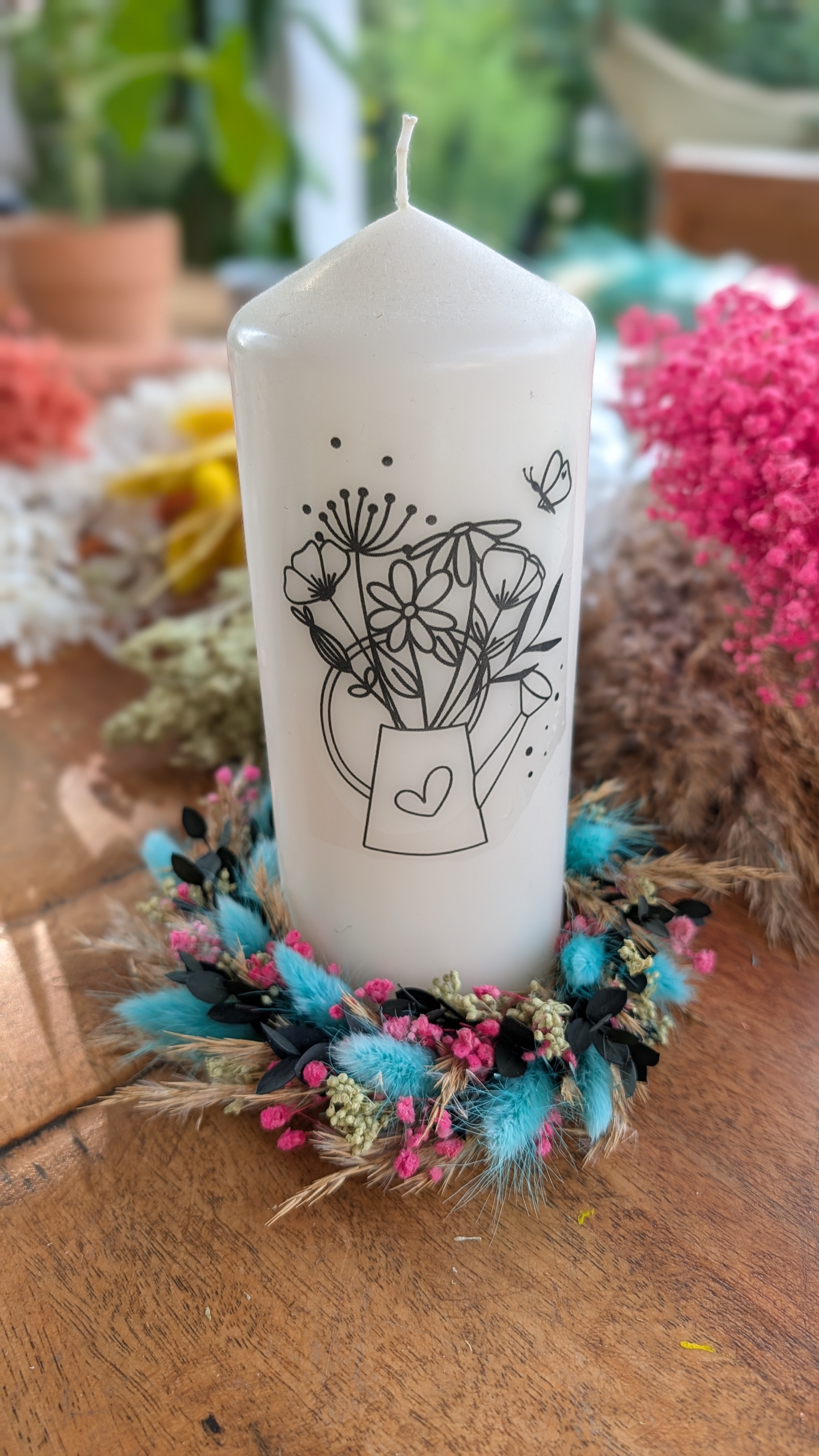 Kerze mit Blumen-Liniendesign und Kerzenkranz aus türkisfarbenen Trockenblumen